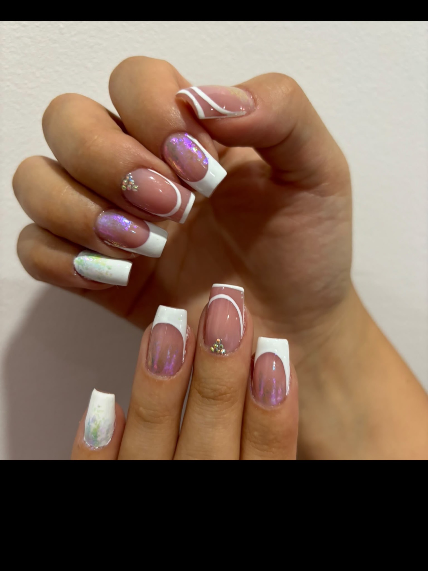 Dos manos con manicura francesa decorada con efecto iridiscente y pedrería